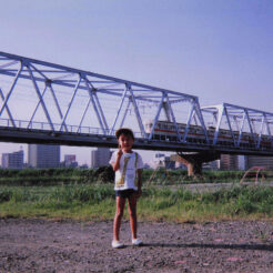 1991-07-28 多摩川の京急の鉄橋前に立つCOTA<br>多摩川の鉄橋前に立っているCOTA。後ろには冷房（エアコン）のついてない都営5000型
