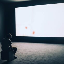 man sitting in front of turned on screen