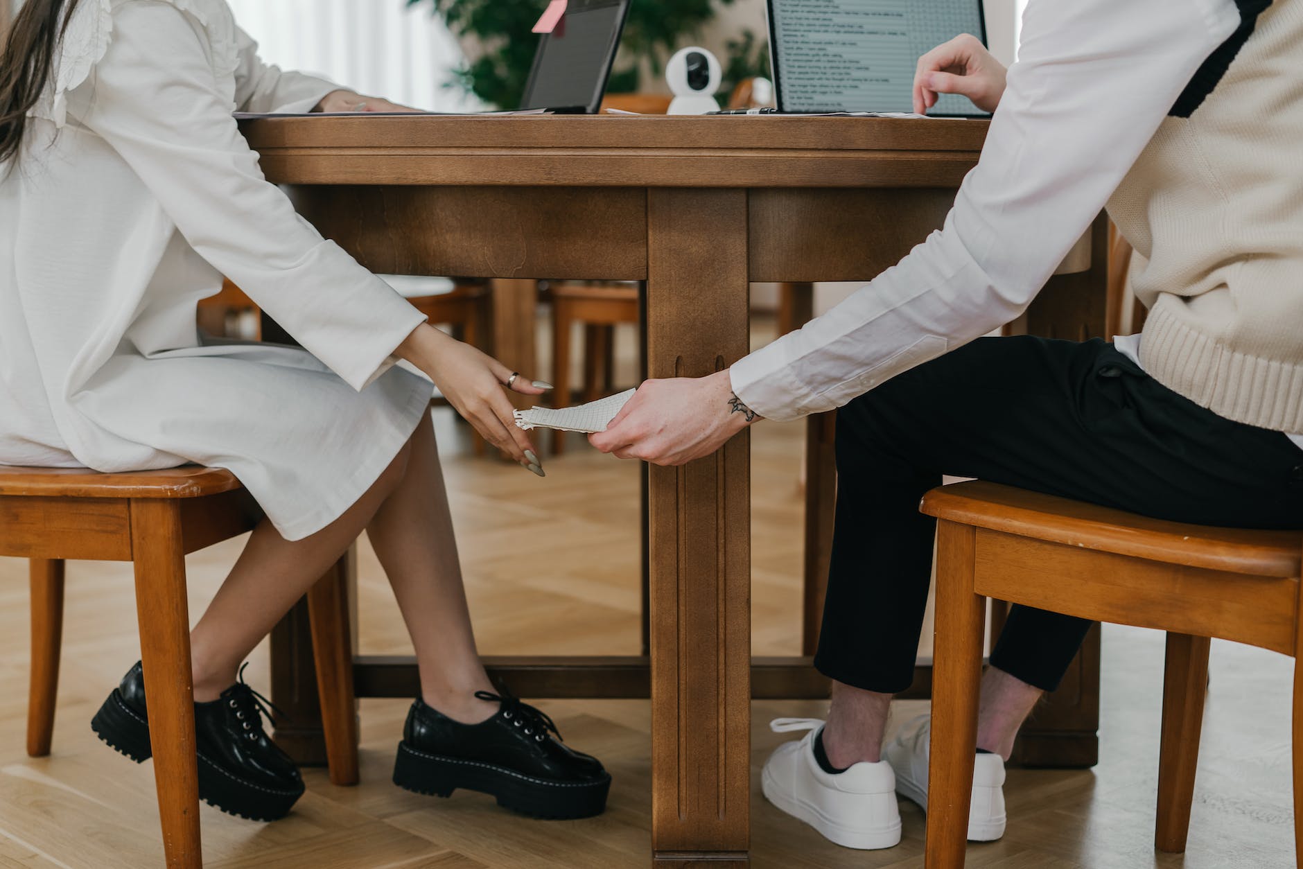 a student passing notes under the table to another person