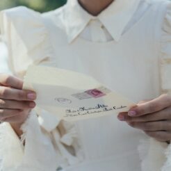 mid section of woman in white dress holding letter